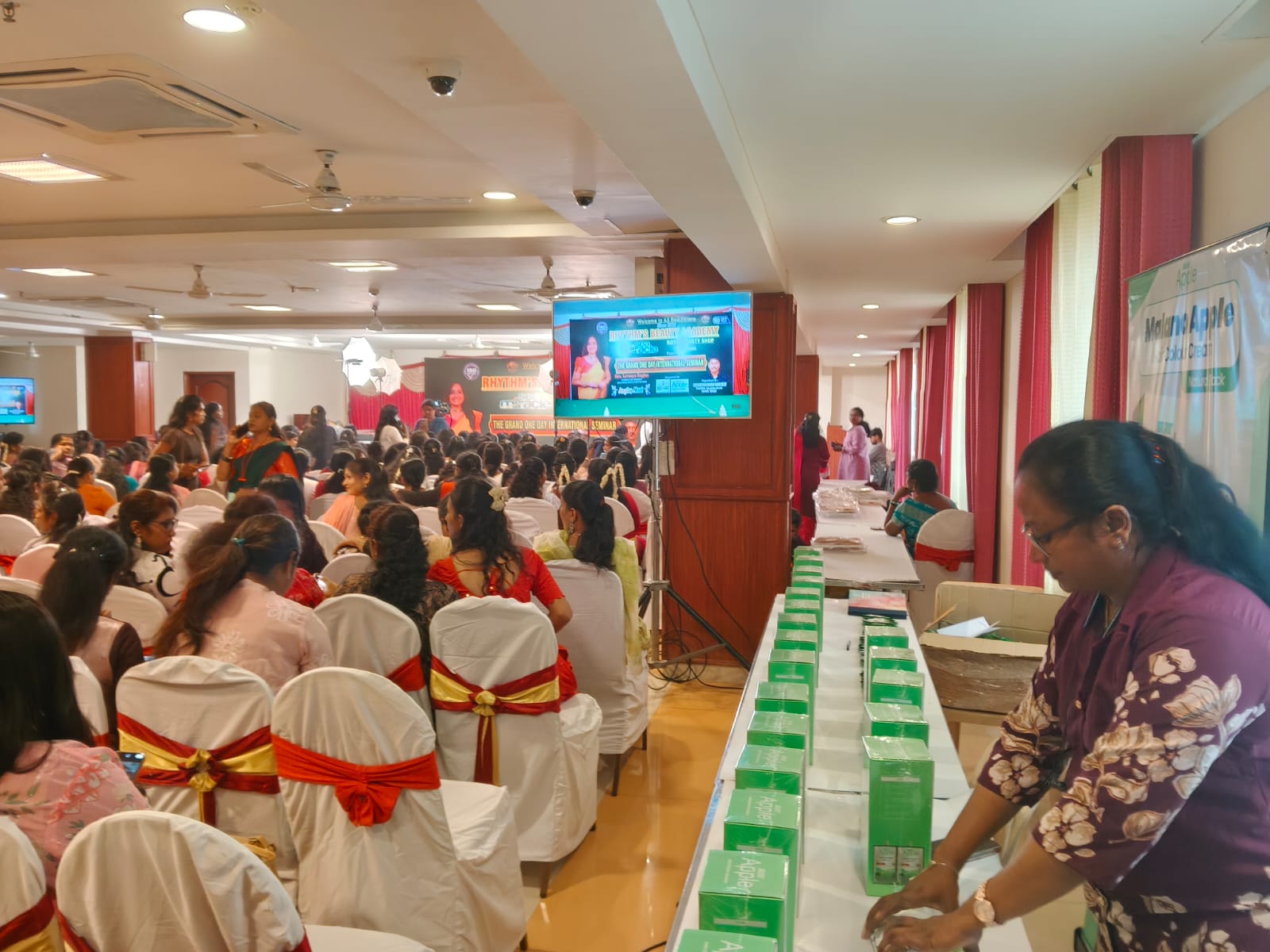 Event hall view with PRIIS product display table and audience seating area