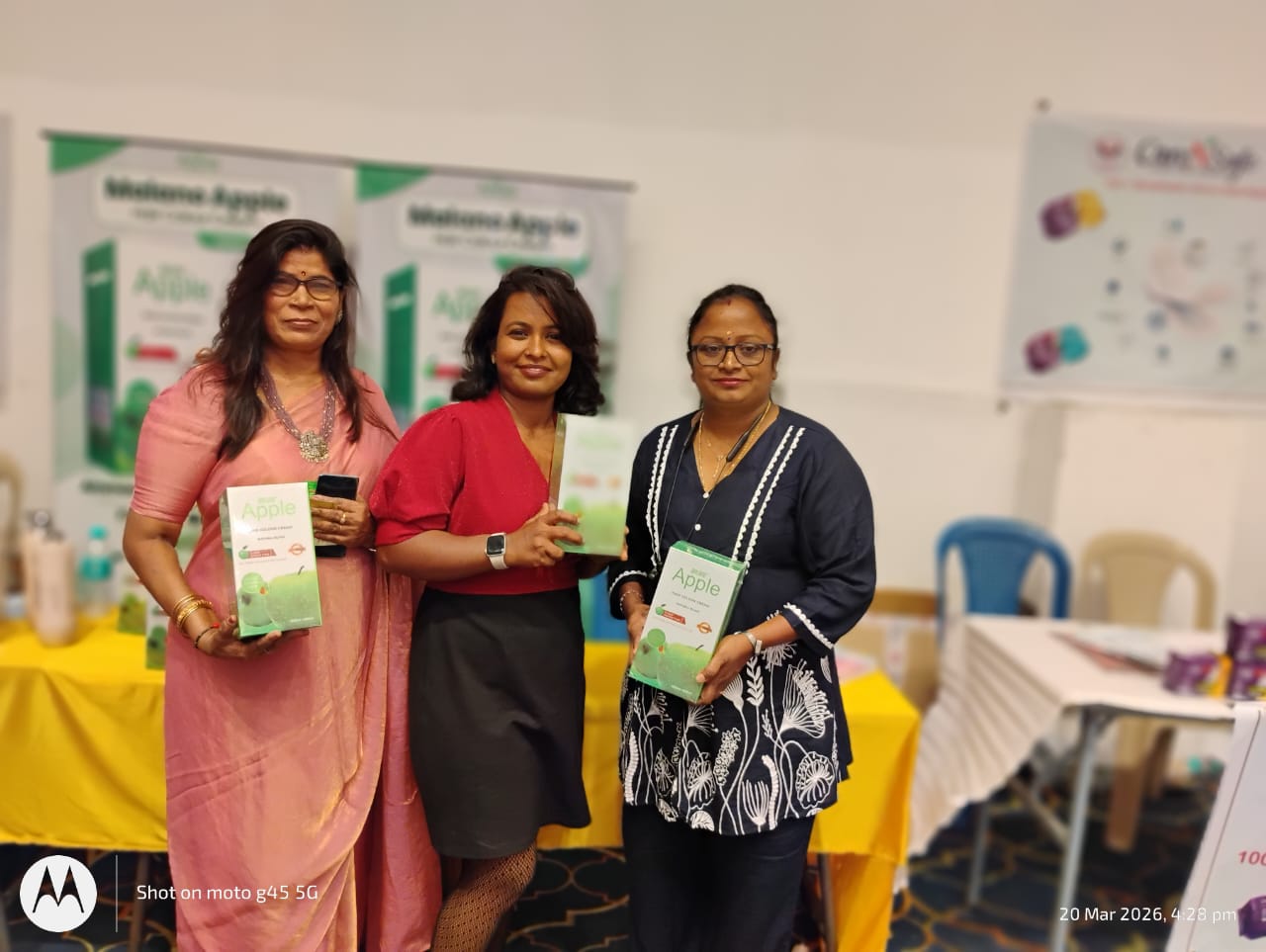 Group of exhibition attendees holding Malano Apple hair colour products during event interaction
